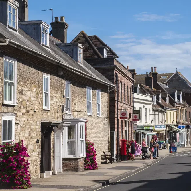 Wareham, Dorset Historic street lined with charming stone houses and shops, adorned with flowering plants.
