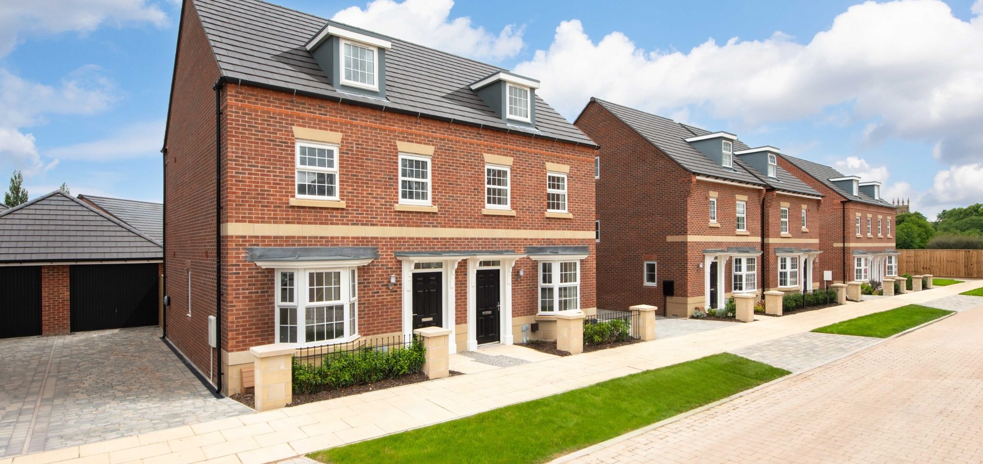 Development Finance A row of modern brick houses with grey roofs and landscaped gardens.