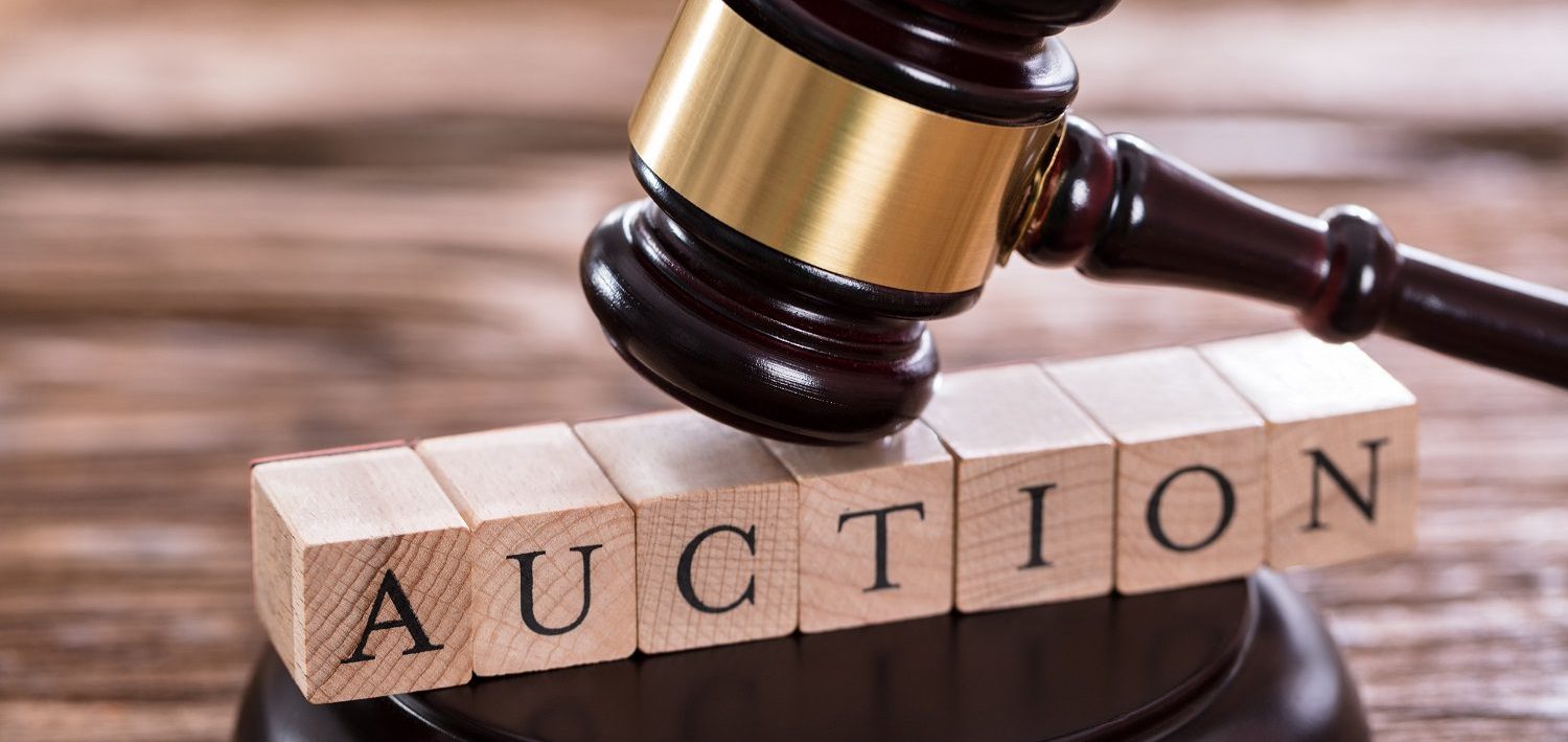 AUCTION A wooden gavel above lettered blocks spelling "AUCTION."