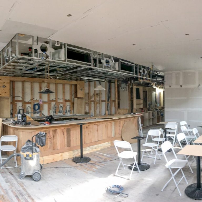 Renovated bar Renovated bar area with unfinished walls, tables, and a wooden counter.