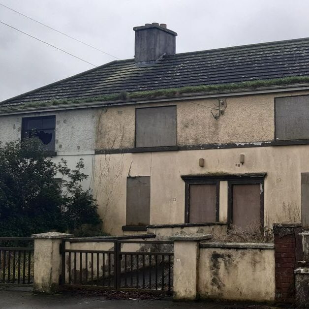 Unlock Your Properties Potential Derelict two-storey house with boarded windows and overgrown vegetation.